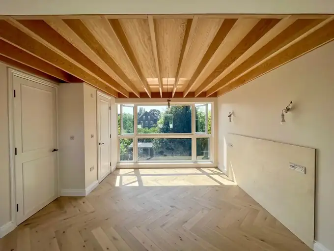 Finished loft bedroom with large windows and herringbone oak floor